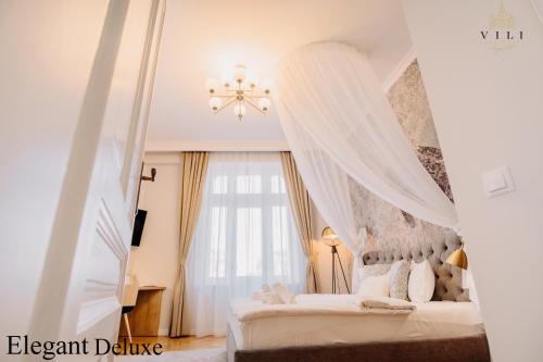 a bedroom with a bed with curtains and a chandelier at Vili Apartments in Oradea