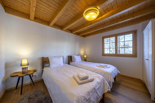 two twin beds in a room with wooden ceilings at Chalet Nid Blanc in Nendaz