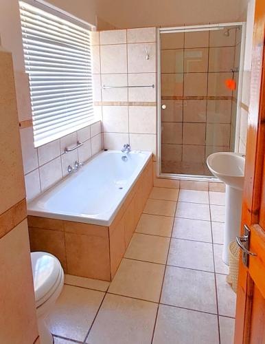 a bathroom with a tub and a toilet and a sink at Donkin House in Beaufort West