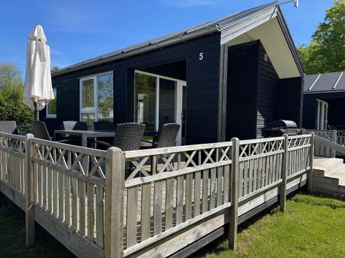a black tiny house with a wooden fence at Rosenvold Strand Camping in Stouby