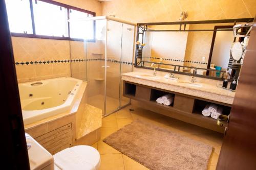 a bathroom with a tub and a sink and a toilet at Hotel das Palmeiras in Paracatu