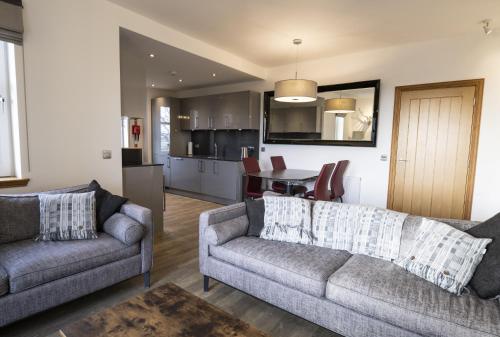 a living room with two couches and a kitchen at Royal Gardens Apartment 10 in Dornoch