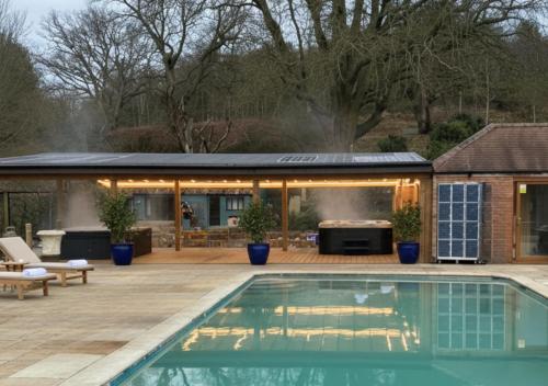 a swimming pool in front of a house with a barbecue at Potton Hall in Saxmundham