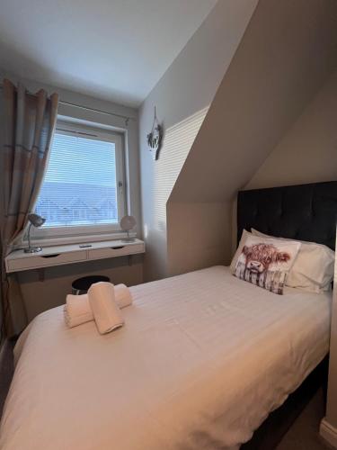 a bedroom with a large white bed with a window at Number 27 in Ullapool