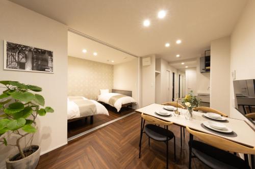 a bedroom with a bed and a dining room with a table at Hotel Kototoi East in Tokyo
