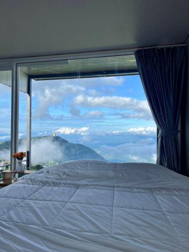a bedroom with a bed and a large window at วิมานหมอก ภูทับเบิก in Ban Maeo Thap Boek