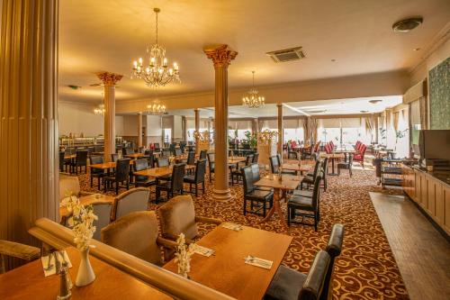 a restaurant with wooden tables and chairs and chandeliers at Royal Bath Hotel Bournemouth in Bournemouth
