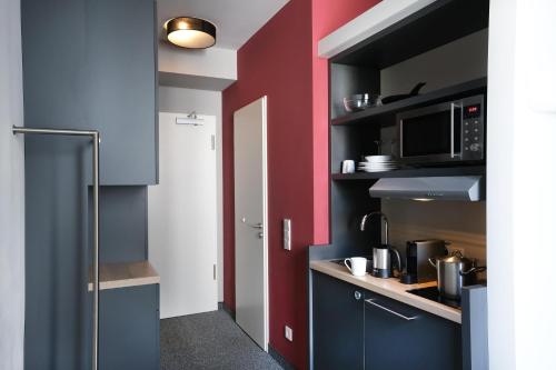 a kitchen with blue cabinets and a red wall at HUB Apartments in Hamburg