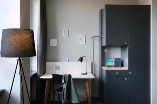 a room with a desk with a lamp and a cabinet at HUB Apartments in Hamburg