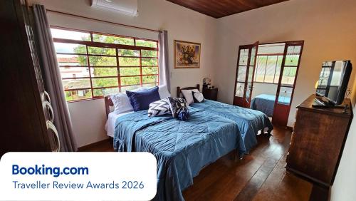 a bedroom with a bed with a blue comforter at Casa dos Coelhos, 750m do centro, até 12 pessoas in Tiradentes