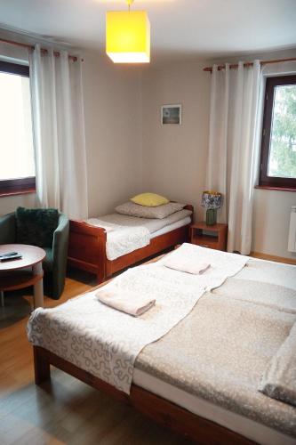 a hotel room with two beds and a chair at Pensjonat Halny Jaworzynka in Jaworzynka