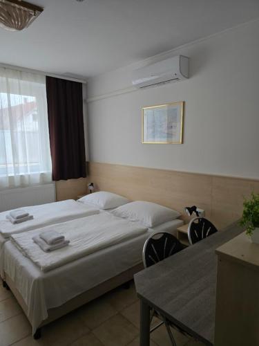 a bedroom with a bed and two chairs and a table at Lencsés Apartmanház Apartmanok in Sopron