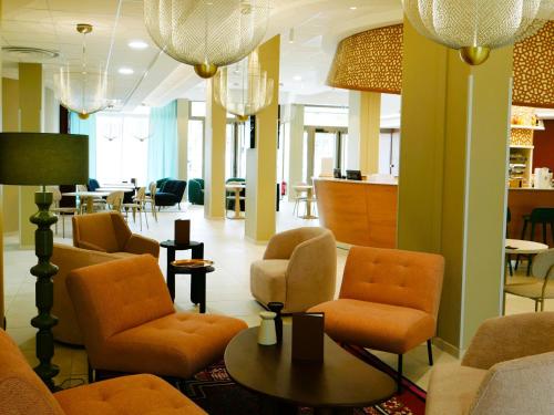 a lobby with orange chairs and a table and a bar at Résidence les Dômes par Vy Resort Thermal & Spa in Vichy