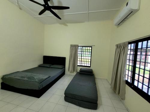 a bedroom with two beds and a ceiling fan at Pangkor Homestay in Pangkor