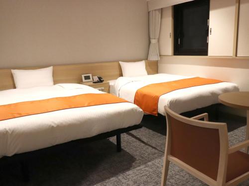 a hotel room with two beds and a table at Tokyo Inn in Tokyo