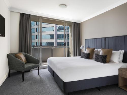 a hotel room with a bed and a chair and a window at Mantra Chatswood in Sydney