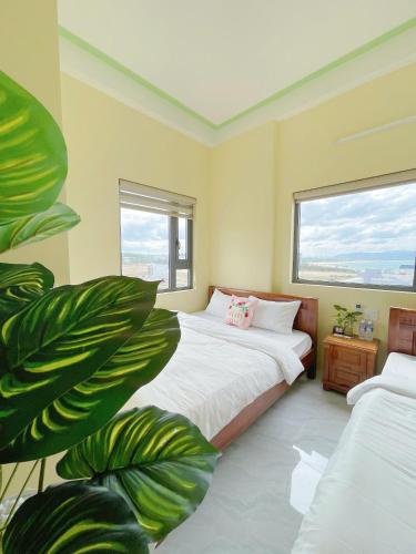 a bedroom with two beds and a large green plant at Homestay Hưởng Thụ - Nhơn Lý in Quy Nhon