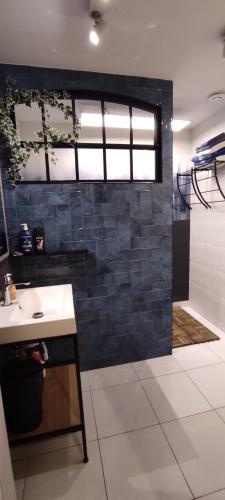 a bathroom with a white sink and a black tile wall at Apartamenty dla par Stara Szkoła in Weremowice