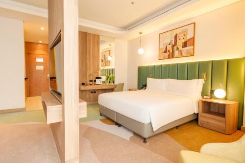 a bedroom with a white bed and a green wall at Edge Riyadh Al Rabie in Riyadh