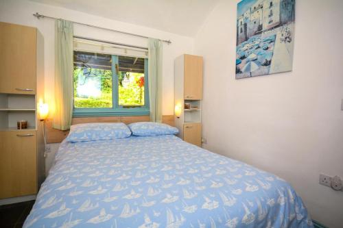 a bedroom with a bed with a blue comforter and a window at 1 Bed in Wadebridge oc-p00223 in Little Petherick