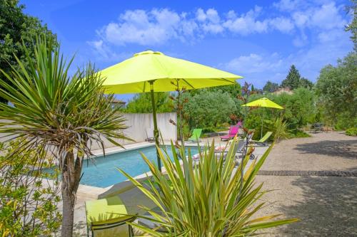 żółty parasol leżący obok basenu w obiekcie Villa Le Cèdre w mieście Saint-Rémy-de-Provence