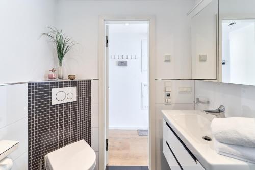 a white bathroom with a toilet and a sink at Sea View Suite in Scharbeutz
