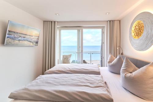 two beds in a bedroom with a view of the ocean at Sea View Suite in Scharbeutz