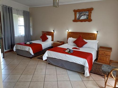 a hotel room with two beds with red and white sheets at Ingwe Guest lodge in Vanderbijlpark
