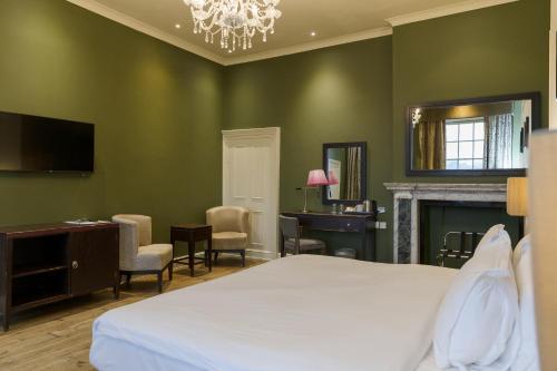 a bedroom with green walls and a bed and a desk at Stoke Place- Part of the Cairn Collection in Slough