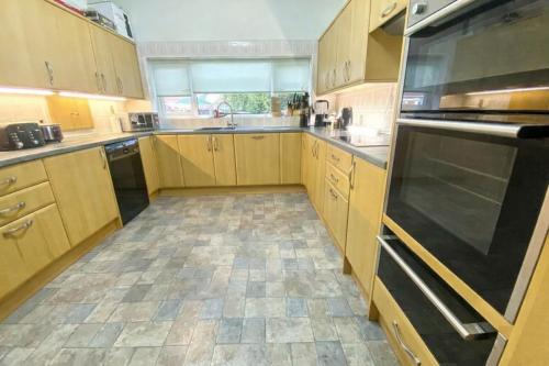 a kitchen with wooden cabinets and a black refrigerator at 3 Bed Bungalow with Large Garden in Westoe