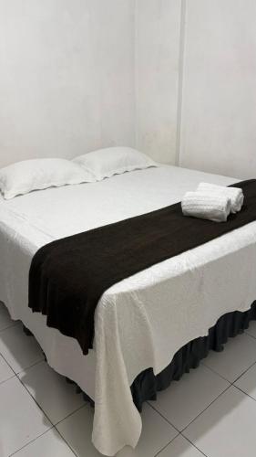 a bed with a black and white blanket on it at Hotel Santiago Juazeiro in Juazeiro do Norte