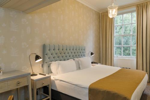 a bedroom with a large bed and a window at Stoke Place- Part of the Cairn Collection in Slough