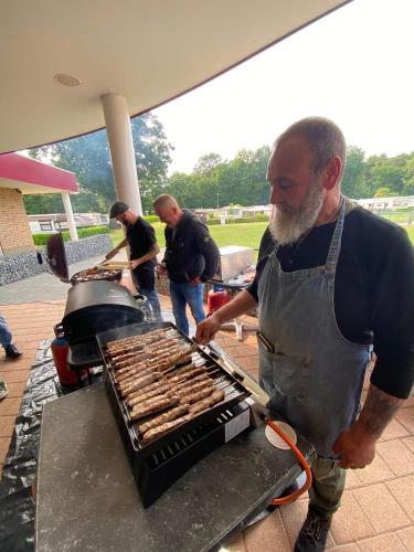 a man is cooking sausages on a grill at Camping San Lanaco in Lanaken