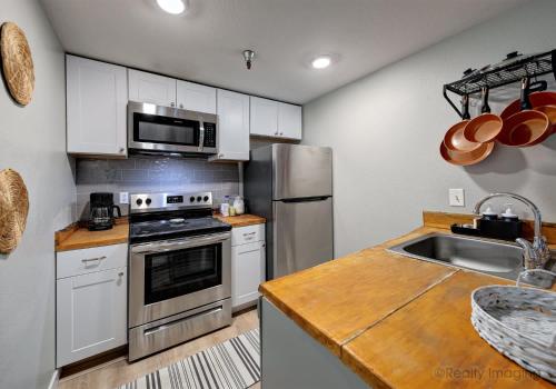 a kitchen with white cabinets and a stainless steel refrigerator at Thunderhead Lodge Condo 204 - Modern Heated Pool & Games in Government Camp