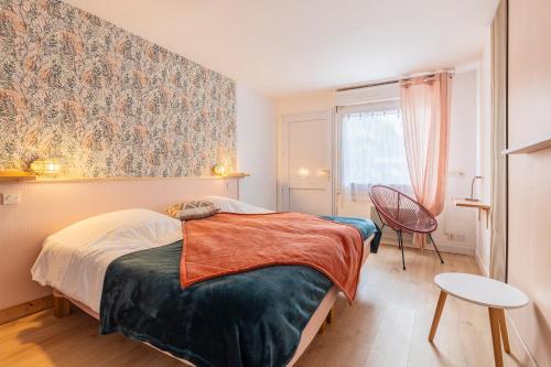 a bedroom with a bed and a chair and a window at Ouest Découvertes in Crozon