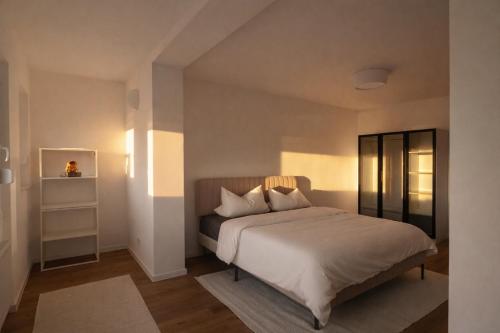 a bedroom with a bed with white sheets and pillows at Seeblick-Apartment am Bodensee bei Konstanz mit großer Terrasse in Reichenau