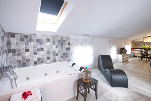 a bathroom with a bath tub and a chair at Apartamentos Cabañas in Carboneras de Guadazaón