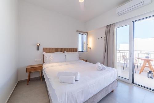 a white bedroom with a bed and a balcony at Elia serenity apartment 4 in Mesochórion