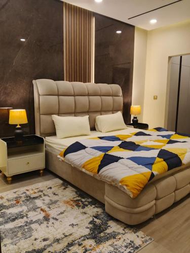 a bedroom with a large bed with a blue and yellow blanket at Premium 3BHK with UPS, across Giga Mall, Pool Included in Islamabad