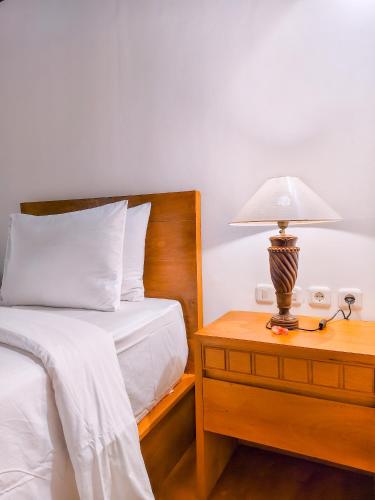 a bedroom with a bed and a lamp on a nightstand at The Kori Sire in Tanjung