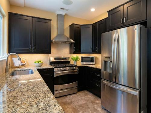 a kitchen with black cabinets and a stainless steel refrigerator at Charming Ranch Retreat in Bear Delaware in Bear