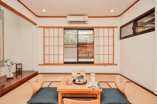 a room with a table and chairs and a window at Chiangrai Ryokan in Ban Long Khi Na