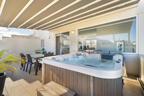 a large bath tub in a room with a table at Cherry Penthouse in Spinola Bay in St. Julianʼs