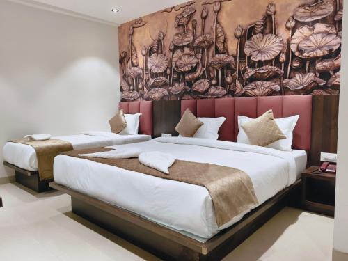 two beds in a hotel room with a painting on the wall at Kings Executive and Restaurant in Tuljapur