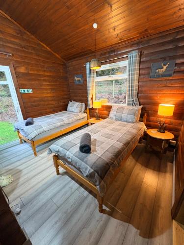 a bedroom with two beds in a log cabin at Antler Lodge Traditional Log Cabin in Dunoon