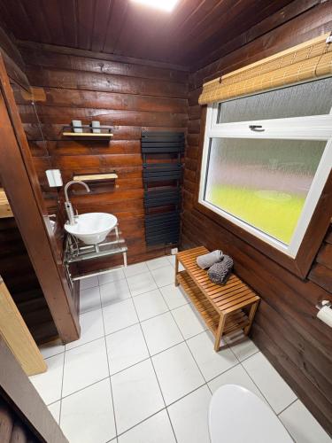 a bathroom with wooden walls and a sink and a window at Antler Lodge Traditional Log Cabin in Dunoon