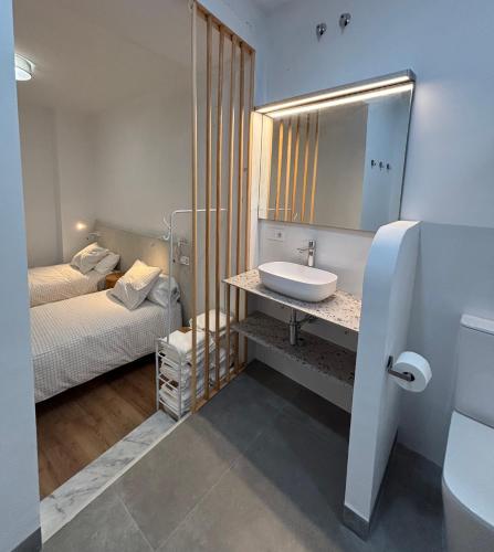 a bathroom with a sink and a bed and a mirror at Cuatro Cantillos in Aguilar de la Frontera