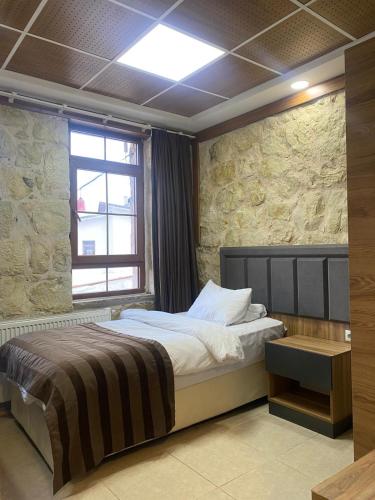 a bedroom with a bed with a stone wall at Kaşkaloğlu Hotel in Arapkir