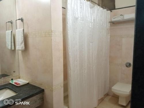 a bathroom with a shower curtain and a toilet at Hotel Mirabel in Jajpur Road