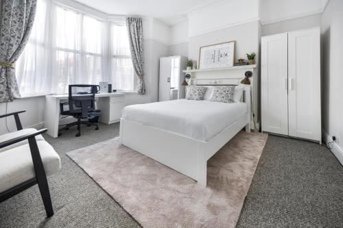 a white bedroom with a white bed and a desk at Cardiff City Guesthouse, Central Rooms, Fast Wi-Fi, On-Street Parking in Cardiff